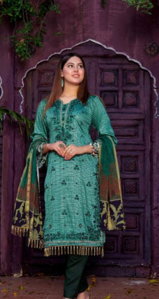 Best salwar suit in kunnamkulam-A woman wearing a green salwar suit with a printed dupatta stands in front of a purple door. A woman wearing a green salwar suit with a printed dupatta stands in front of a purple door.