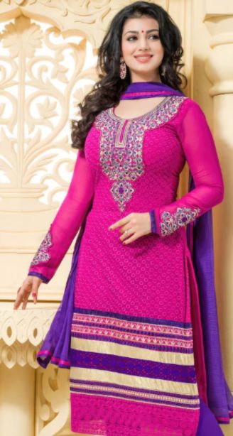 Best salwar suit in kunnamkulam-A woman in a pink and purple salwar suit stands indoors, smiling.
